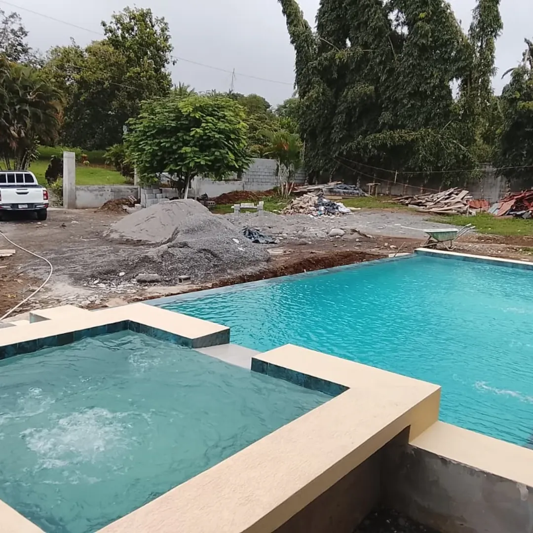 Piscina de borde infinito terminada con el terreno todavía en obra