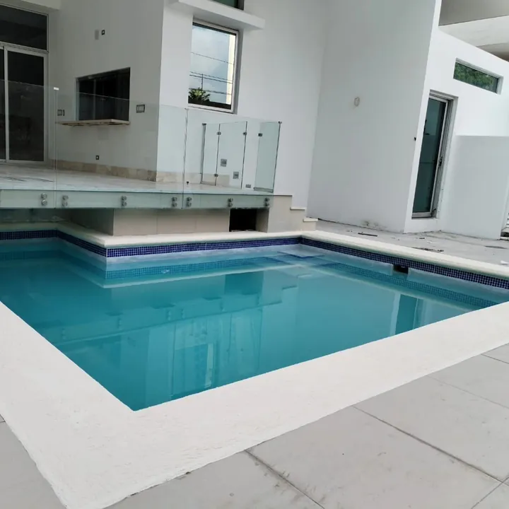 Piscina con barandal de vidrio junto a una casa moderna en Chiriquí