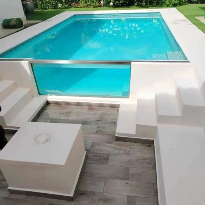 Piscina turquesa con borde de descanso y terraza de concreto