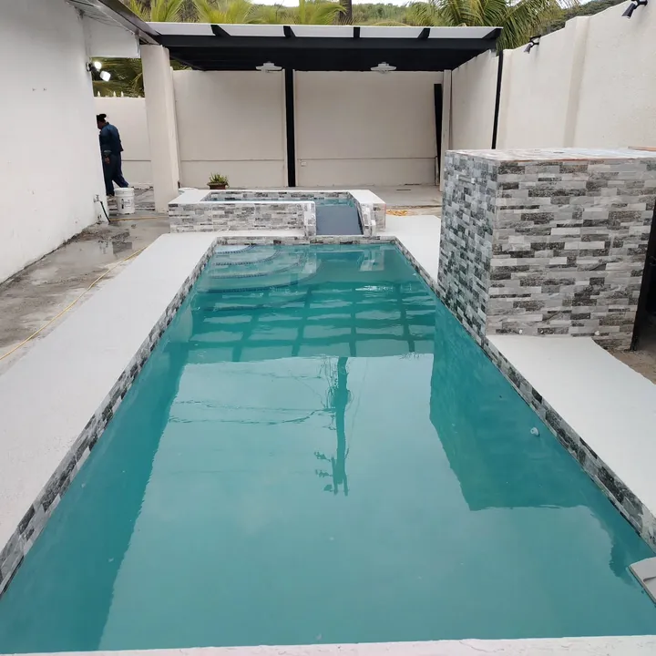 Piscina alargada tipo carril con muro revestido en piedra