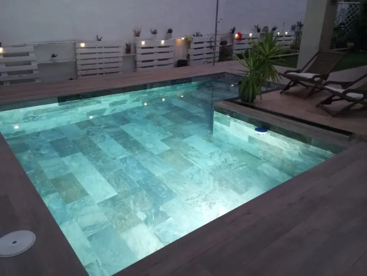 Piscina con deck de madera y zona de descanso