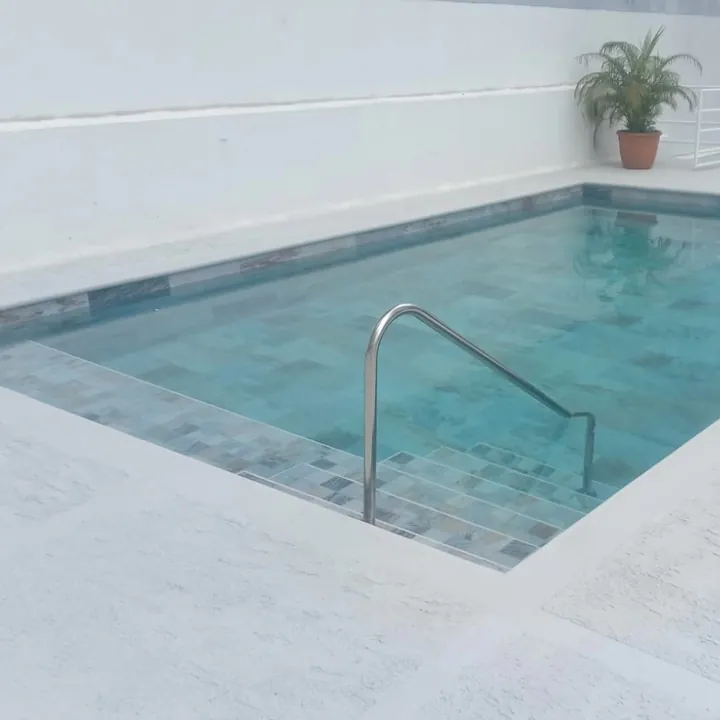 Piscina de PH remodelada con acabado turquesa y deck blanco